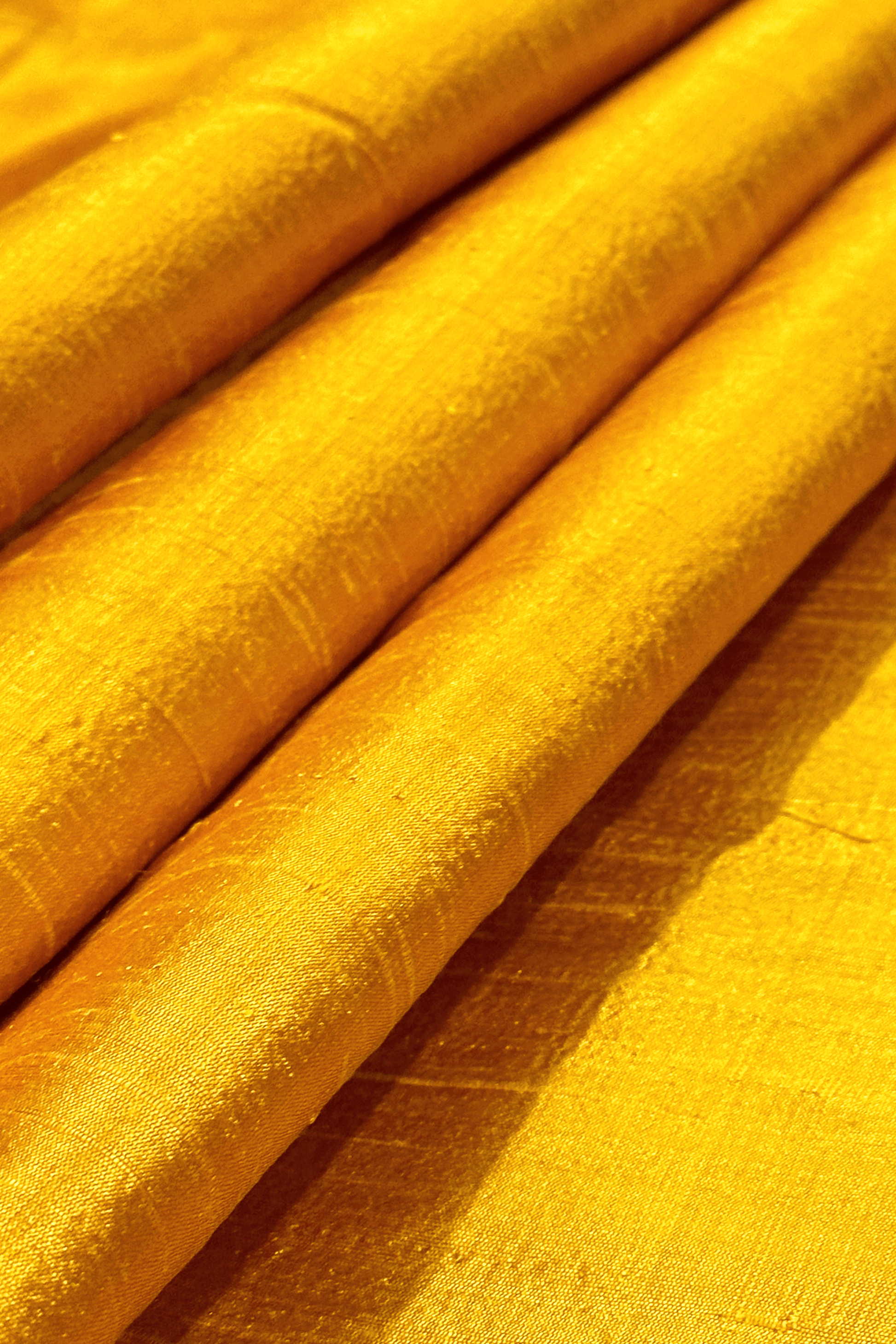 Close-up of saffron yellow raw silk fabric with a textured pattern