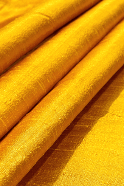 Close-up of saffron yellow raw silk fabric with a textured pattern