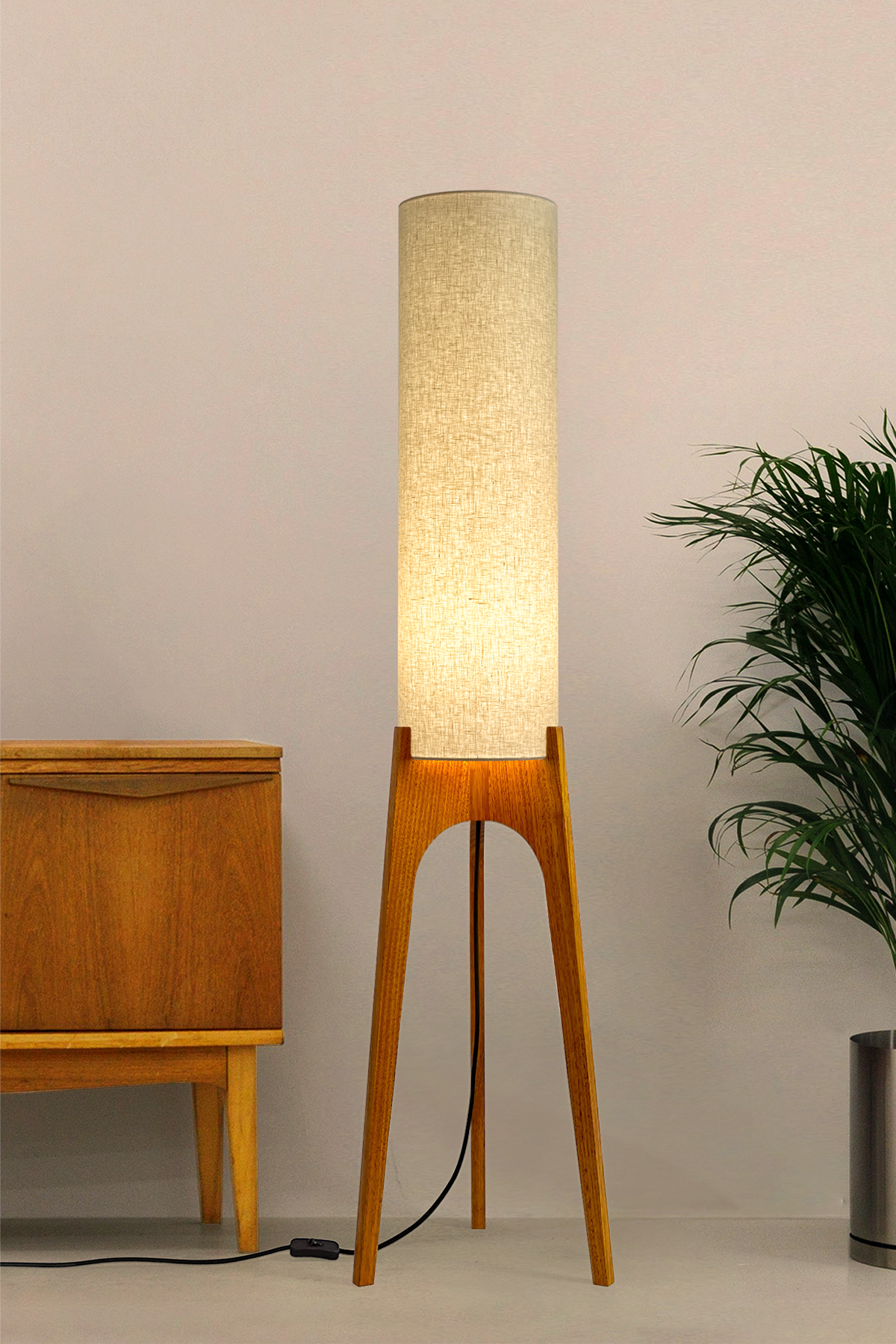 Sesame - Archie Rocket Floor Lamp by Retro Duo, featuring a handcrafted wooden base and beige cylindrical shade, styled beside a wooden cabinet and plant against a light grey background.