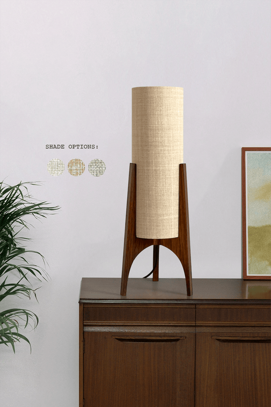 Archie Rocket Table lamp with wooden base and recycled fabric shade on with a plant and artwork in the background.