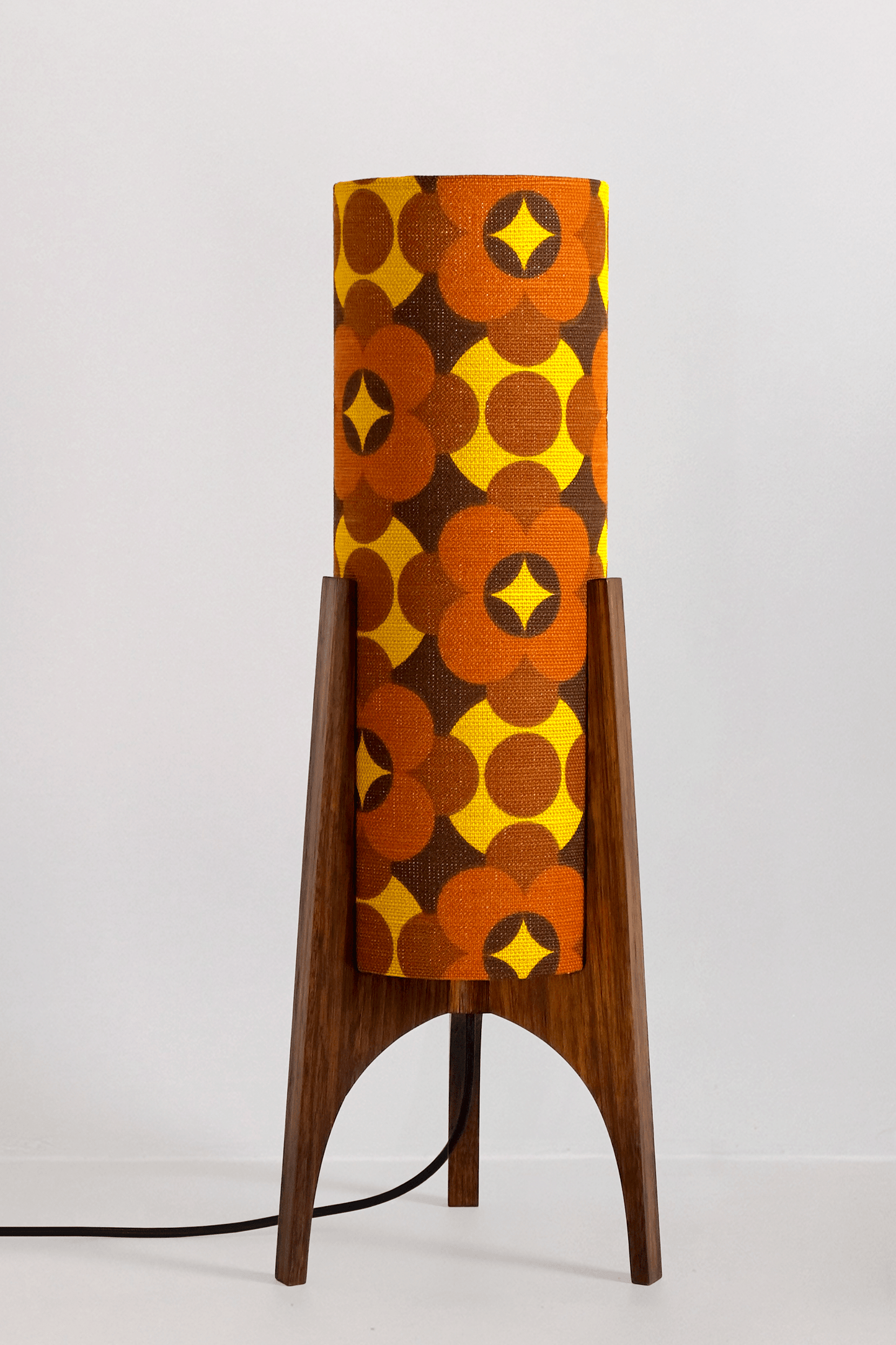 Coco - Archie Rocket Table lamp with a vintage geometric patterned fabric shade on a wooden cabinet against a white wall.